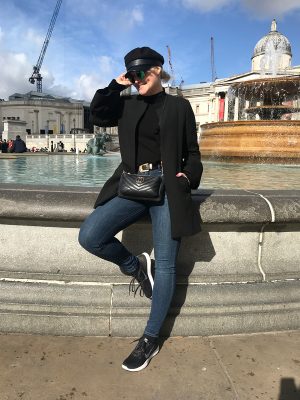 Lorna Weightman wearing black coat, jeans and black trainers, in front of Trafalgar square London
