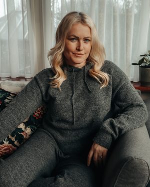 Lorna Weightman pictured sitting in a room with natural light and wearing a grey wool top and trousers