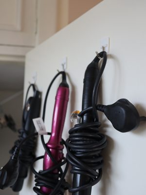 Image of electrical hair tools hanging on small hooks