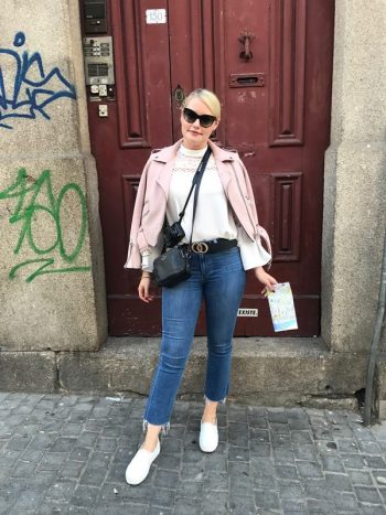 Lorna Weightman pictured wearing pink jacket, jeans also wearing sunglasses and holding a map pictured in front of a red door