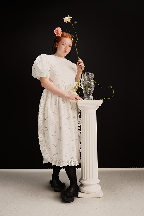 Image showing female wearing white dress, black socks and shoes holding a pink flower