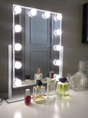 Image of mirror with lights around it with perfume bottles lined in front on a white desk