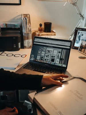 Image of laptop on a desk with a printer, pictures and picture frames as part of how to style a gallery wall